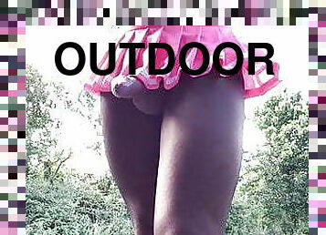 Cock in pink mini skirt outdoors .