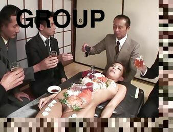 Group of business men eat sushi off her beautiful body