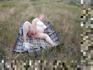 fat woman masturbates with a toy in the field