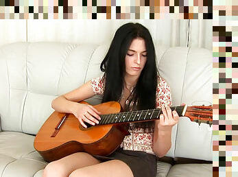 Dark-haired musician Larisa is playing on the guitar